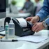 Technician repairing thermal printer with tools on an office desk.